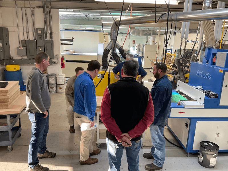 A group of men observing a Dubois finishing machine